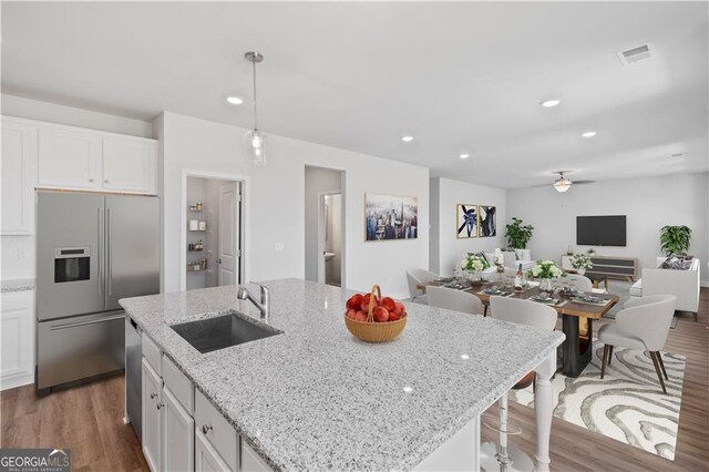 kitchen featuring hardwood / wood-style floors, white cabinetry, decorative light fixtures, and stainless steel appliances