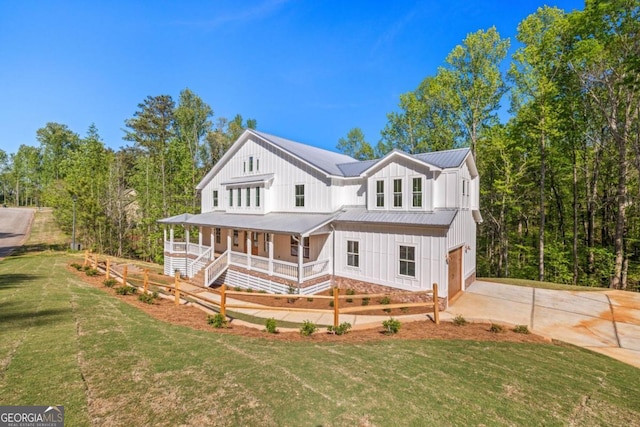 modern farmhouse style home featuring covered porch, a garage, and a front lawn