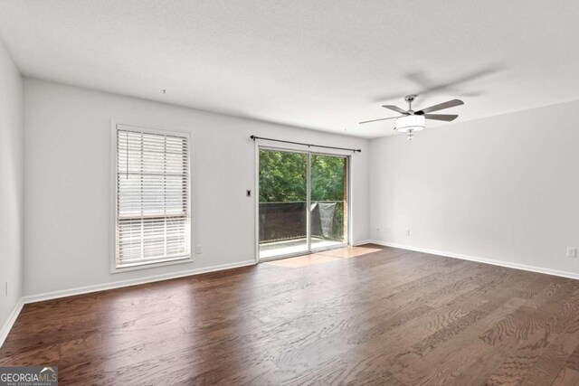 unfurnished room featuring a textured ceiling, ceiling fan, and dark wood-type flooring