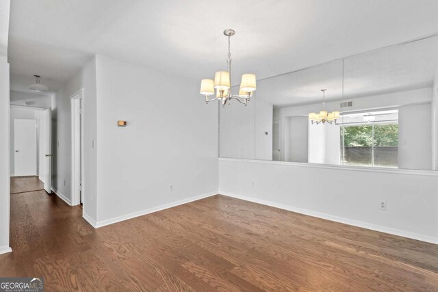 unfurnished room with dark hardwood / wood-style flooring and a chandelier