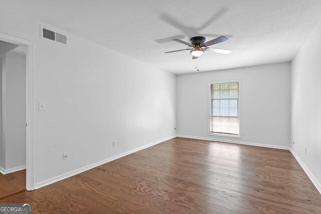 empty room featuring ceiling fan and dark hardwood / wood-style flooring