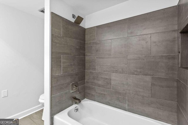 bathroom with tile patterned floors, tiled shower / bath combo, and toilet