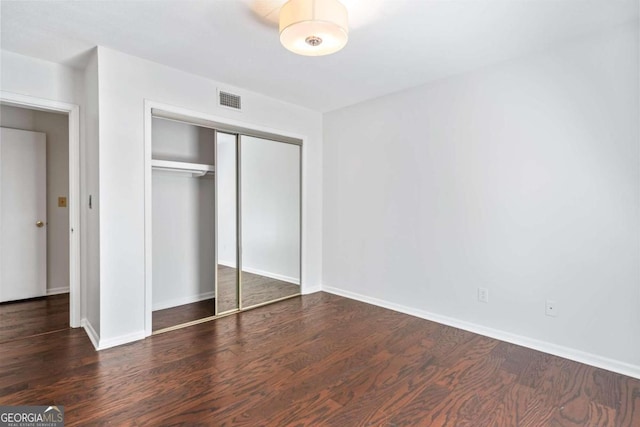 unfurnished bedroom with dark hardwood / wood-style floors and a closet