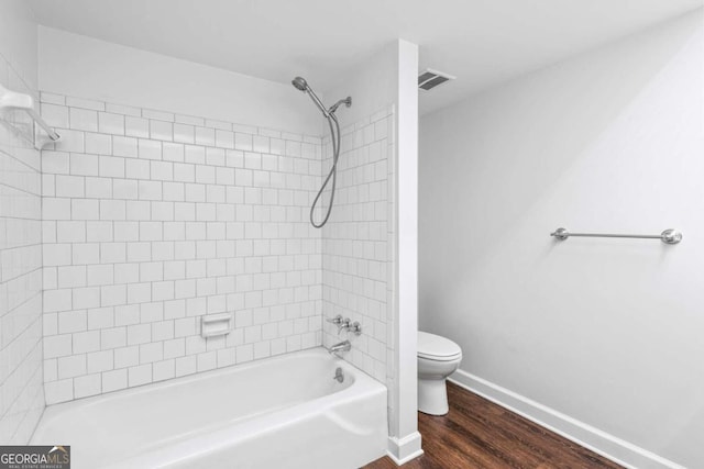 bathroom with toilet, tiled shower / bath, and hardwood / wood-style flooring