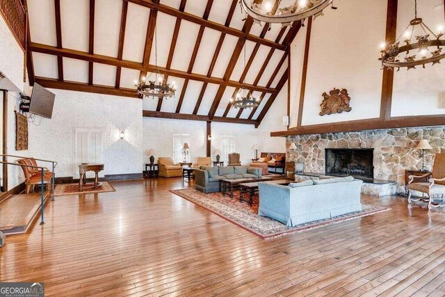 living room featuring hardwood / wood-style flooring, high vaulted ceiling, and a stone fireplace