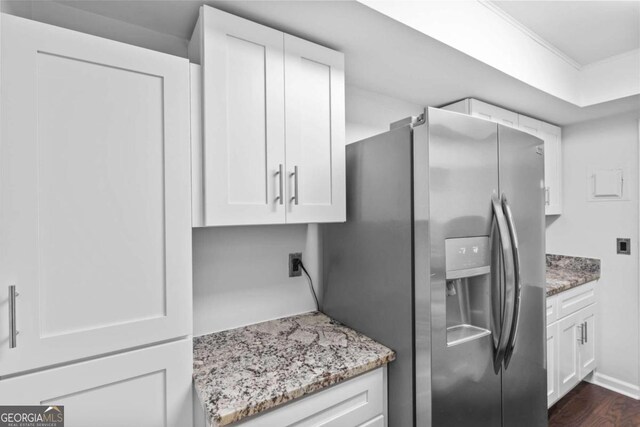 kitchen with white cabinetry, stainless steel fridge, light stone counters, and dark hardwood / wood-style floors