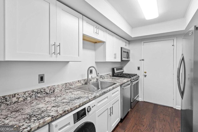 kitchen with dark wood-type flooring, white cabinets, sink, washer / dryer, and stainless steel appliances