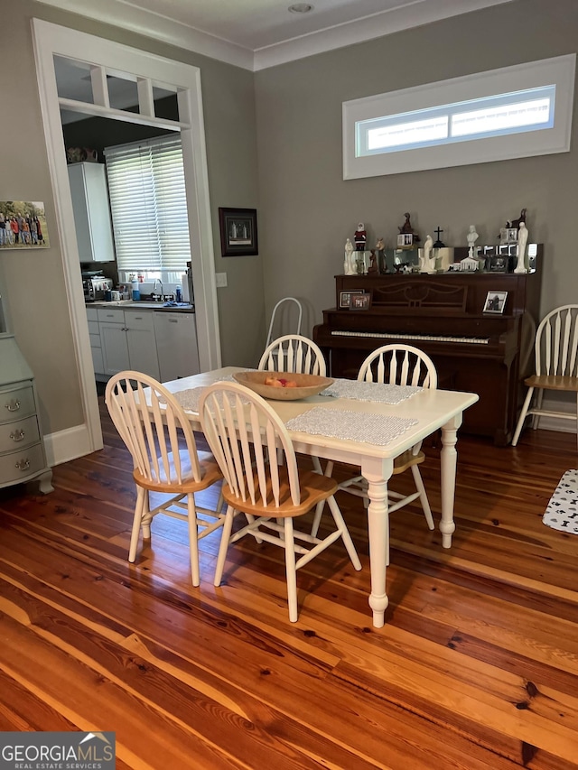 dining area featuring crown molding, dark wood-type flooring, and sink