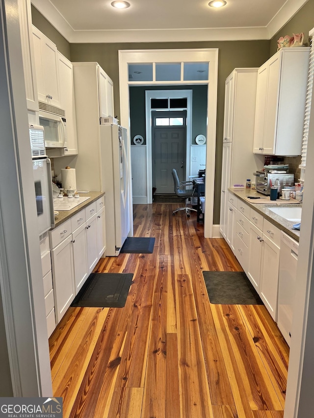 kitchen featuring white cabinets, dark hardwood / wood-style floors, light stone counters, and white appliances