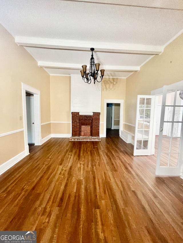 unfurnished living room with hardwood / wood-style flooring, a notable chandelier, a textured ceiling, and beamed ceiling