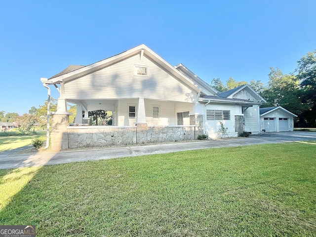 view of front of property featuring a garage, a front lawn, and an outbuilding