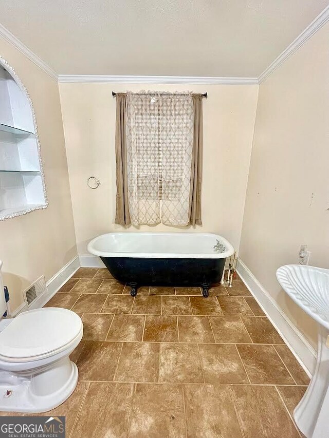 bathroom featuring tile patterned flooring, toilet, a tub to relax in, and crown molding