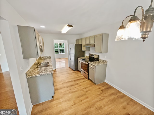 kitchen with appliances with stainless steel finishes, light stone counters, gray cabinetry, sink, and light hardwood / wood-style flooring