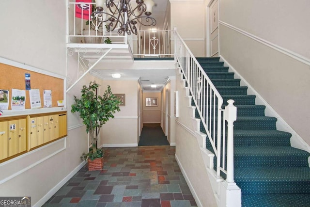 staircase featuring ornamental molding, an inviting chandelier, and dark tile floors