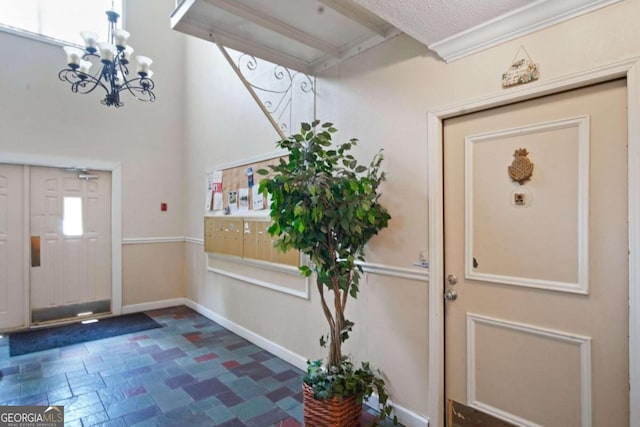 tiled foyer entrance featuring a chandelier, a textured ceiling, and crown molding