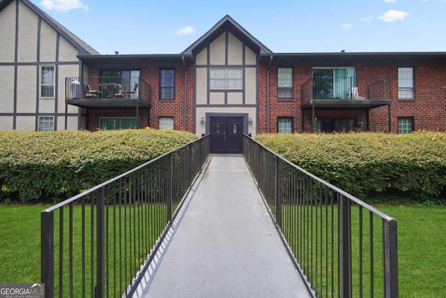 view of front of property featuring a front lawn and a balcony