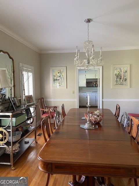 dining area with crown molding, hardwood / wood-style floors, and an inviting chandelier