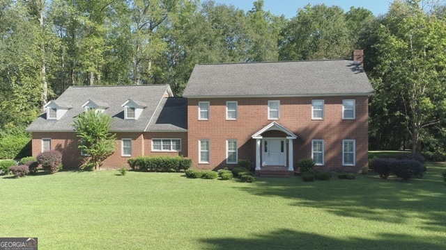 colonial inspired home featuring a front lawn