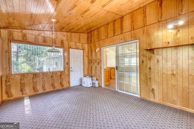 spare room with wood ceiling, wood walls, carpet floors, and vaulted ceiling