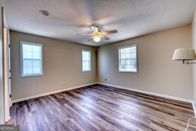 empty room with a wealth of natural light, hardwood / wood-style flooring, and ceiling fan