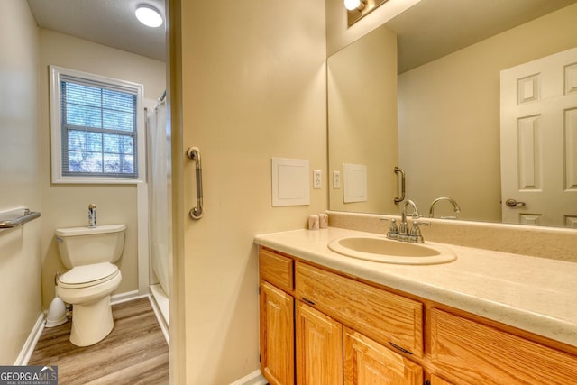 bathroom featuring wood-type flooring, vanity with extensive cabinet space, and toilet