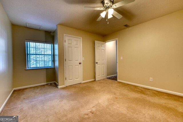 unfurnished bedroom with a textured ceiling, ceiling fan, and light colored carpet