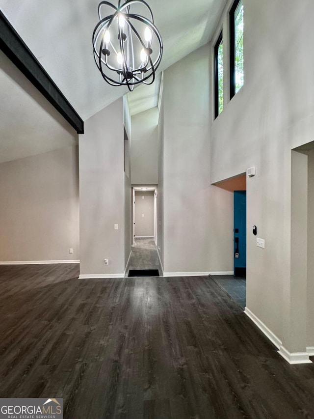 entryway with dark wood-type flooring, a chandelier, and high vaulted ceiling