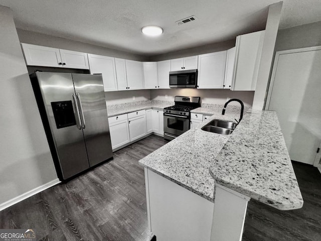 kitchen with kitchen peninsula, sink, stainless steel appliances, and white cabinetry