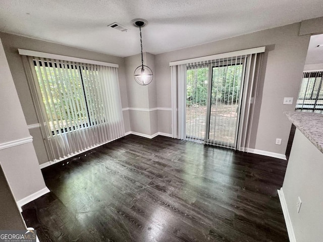 unfurnished dining area with dark hardwood / wood-style floors and a textured ceiling