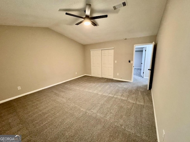 unfurnished bedroom featuring ceiling fan, carpet floors, lofted ceiling, a textured ceiling, and a closet