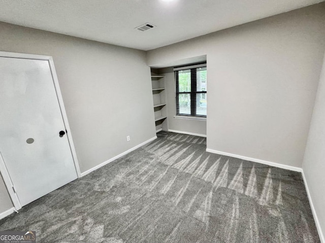 unfurnished bedroom with dark colored carpet