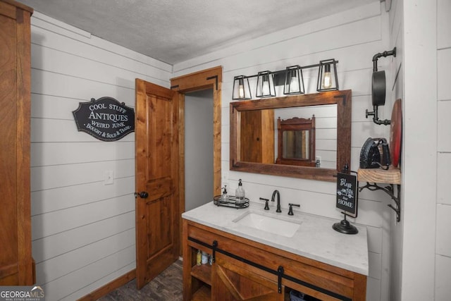 bathroom featuring vanity, a textured ceiling, and wooden walls