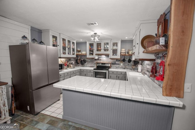 kitchen with decorative backsplash, stainless steel appliances, sink, white cabinets, and tile counters