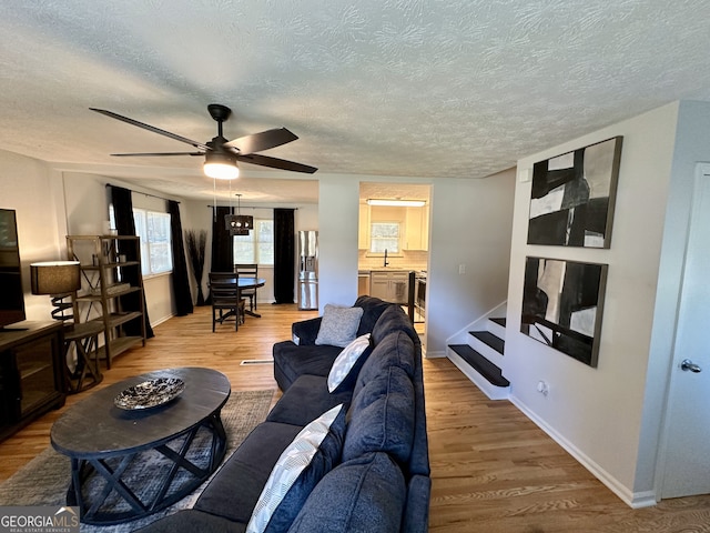 living room featuring a textured ceiling, ceiling fan, and hardwood / wood-style flooring