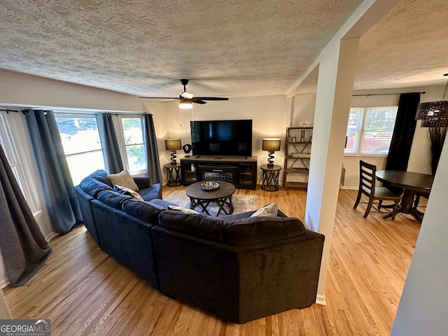 living room with a textured ceiling, a healthy amount of sunlight, ceiling fan, and light hardwood / wood-style flooring