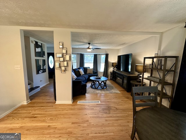 living room with ceiling fan, light hardwood / wood-style floors, and a textured ceiling