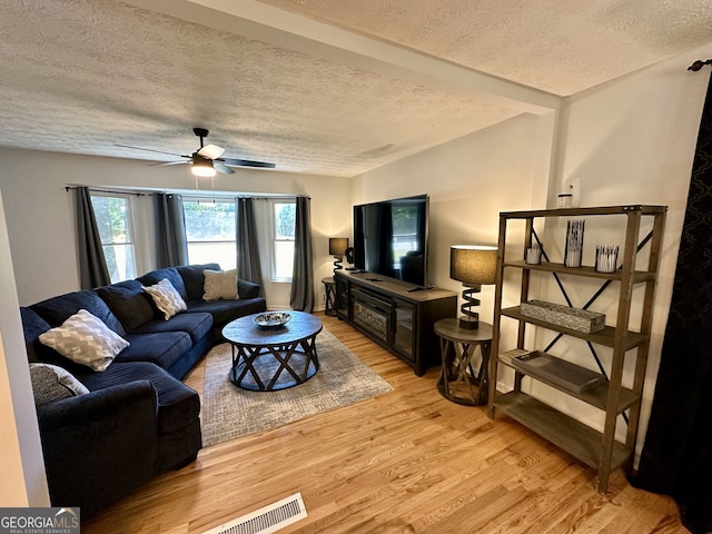 living room with a textured ceiling, ceiling fan, and light hardwood / wood-style floors