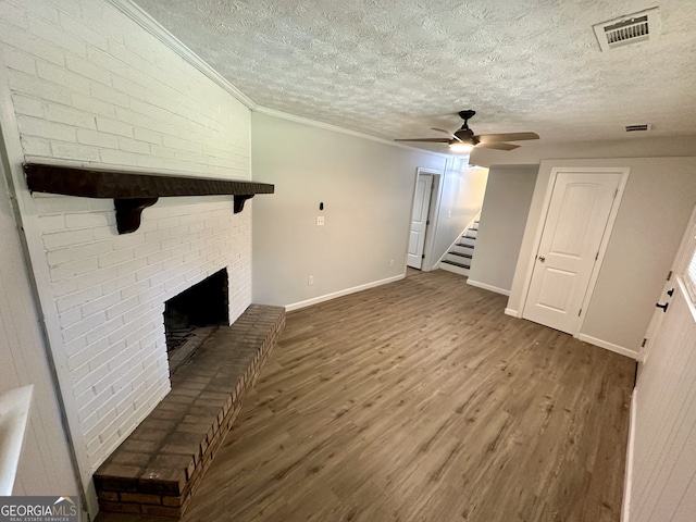 unfurnished living room with a fireplace, crown molding, a textured ceiling, wood-type flooring, and ceiling fan