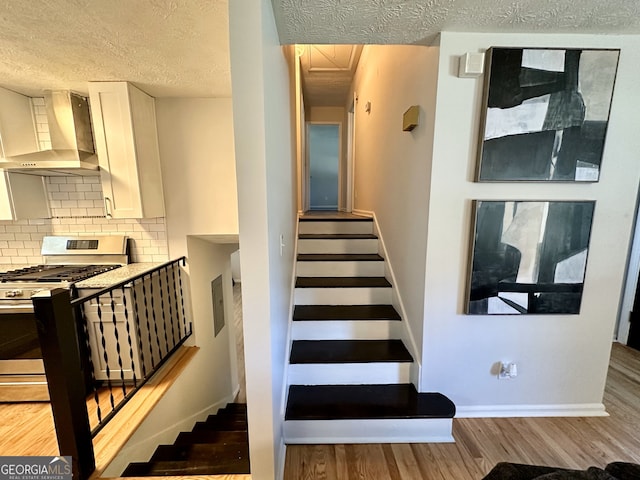 stairway featuring a textured ceiling and hardwood / wood-style floors