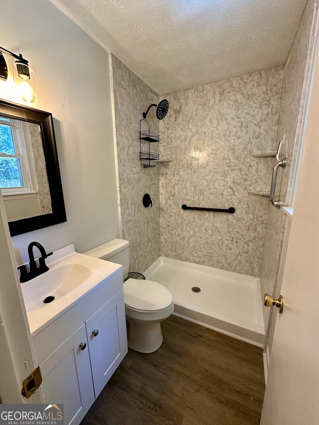 bathroom with walk in shower, hardwood / wood-style flooring, a textured ceiling, and vanity