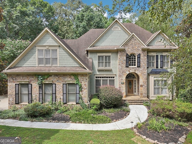 craftsman house featuring stone siding and roof with shingles