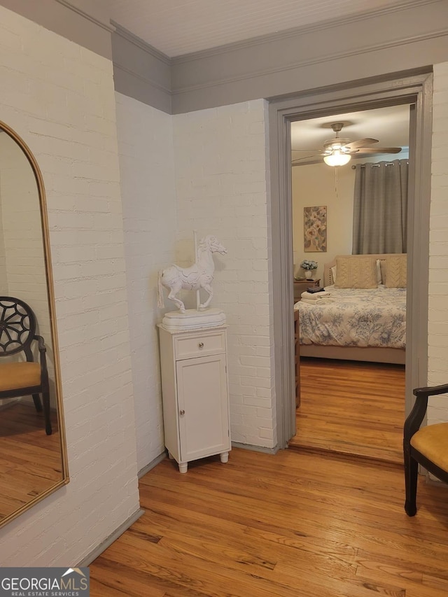 hallway featuring light hardwood / wood-style flooring, brick wall, and ornamental molding