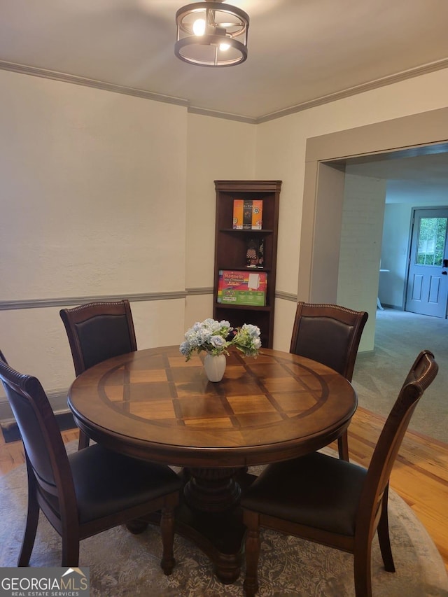 dining space with hardwood / wood-style flooring and ornamental molding