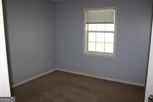 spare room featuring dark colored carpet