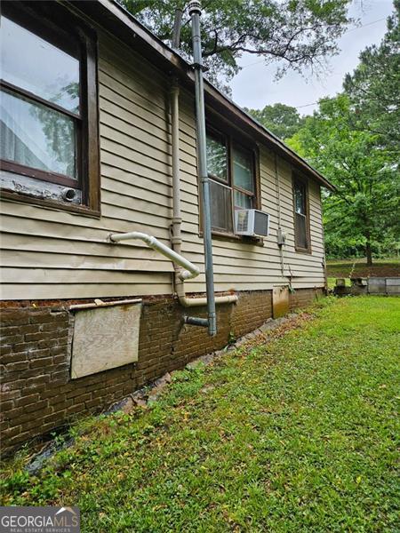 view of side of home with cooling unit and a yard