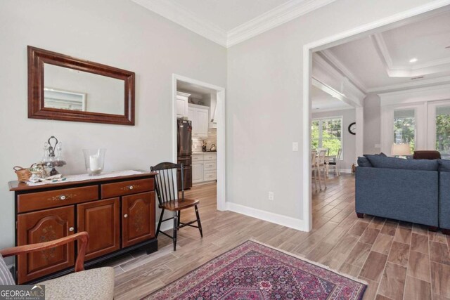 hall featuring a raised ceiling, light hardwood / wood-style floors, and crown molding