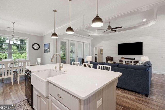 kitchen with a kitchen island with sink, pendant lighting, and wood-type flooring