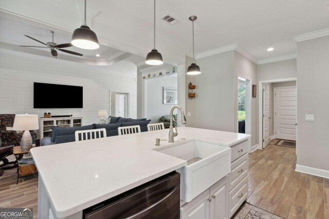 kitchen with dishwasher, light hardwood / wood-style floors, a kitchen island with sink, and pendant lighting