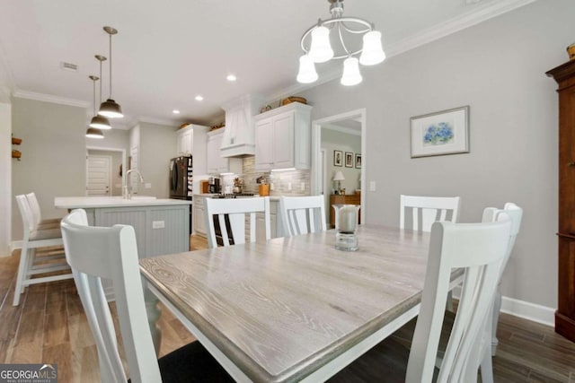 dining area with a notable chandelier, wood-type flooring, and ornamental molding