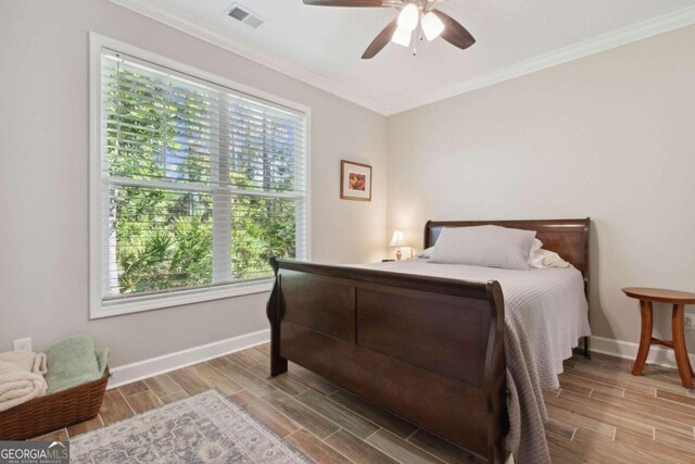 bedroom featuring hardwood / wood-style floors, ceiling fan, and crown molding